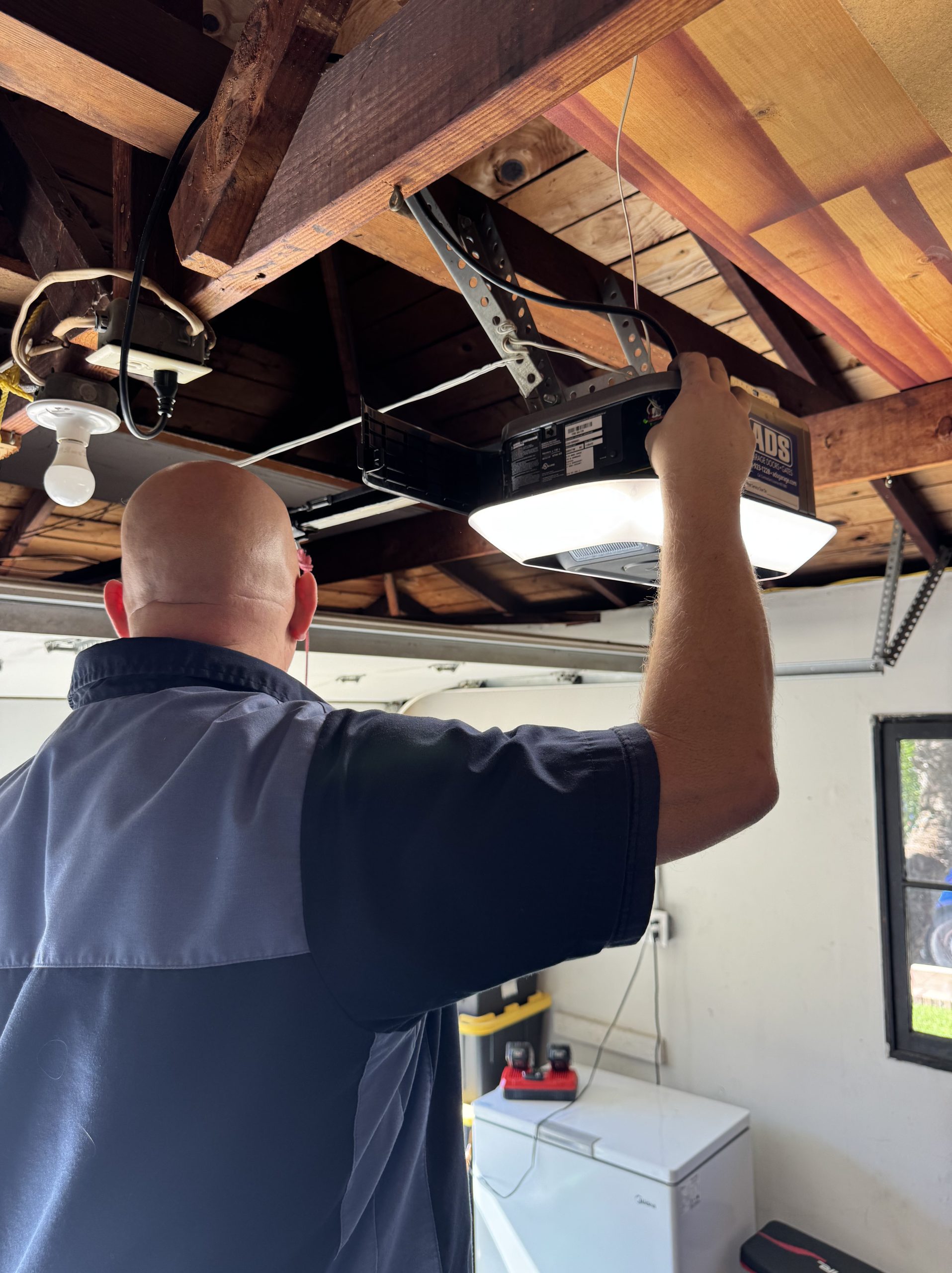 Technician installing garage door opener unit